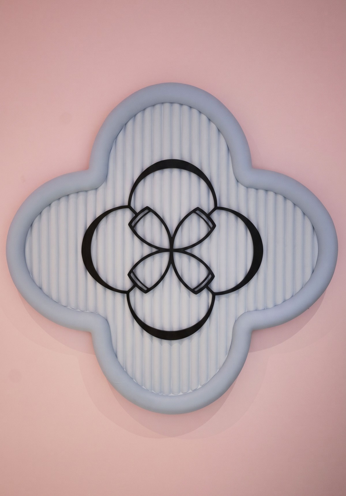 Four-petal flower logo mounted on a fluted partition panel